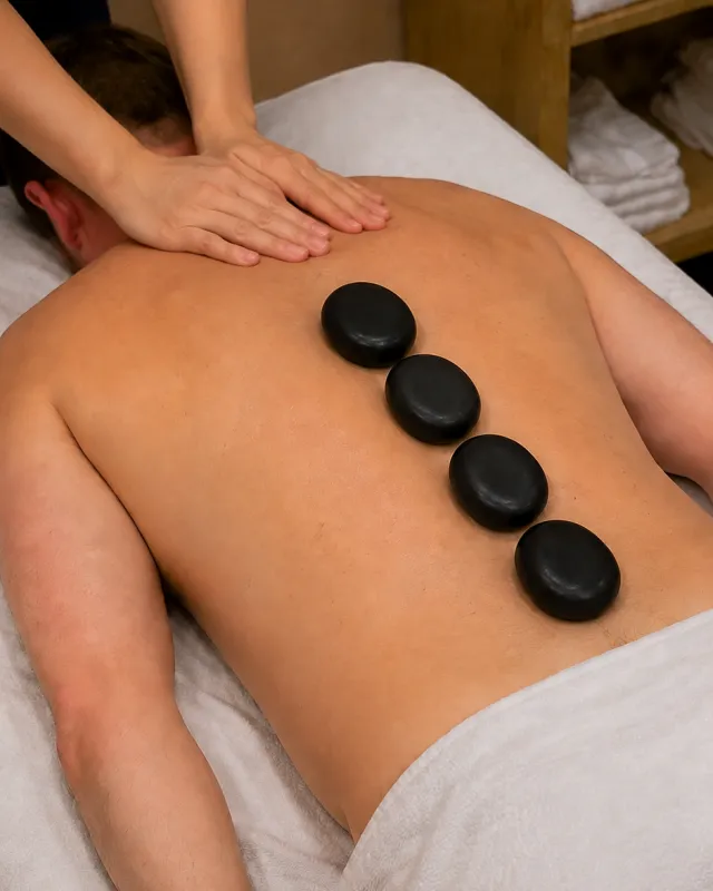 Warm stones placed along a draped guest's back during a massage