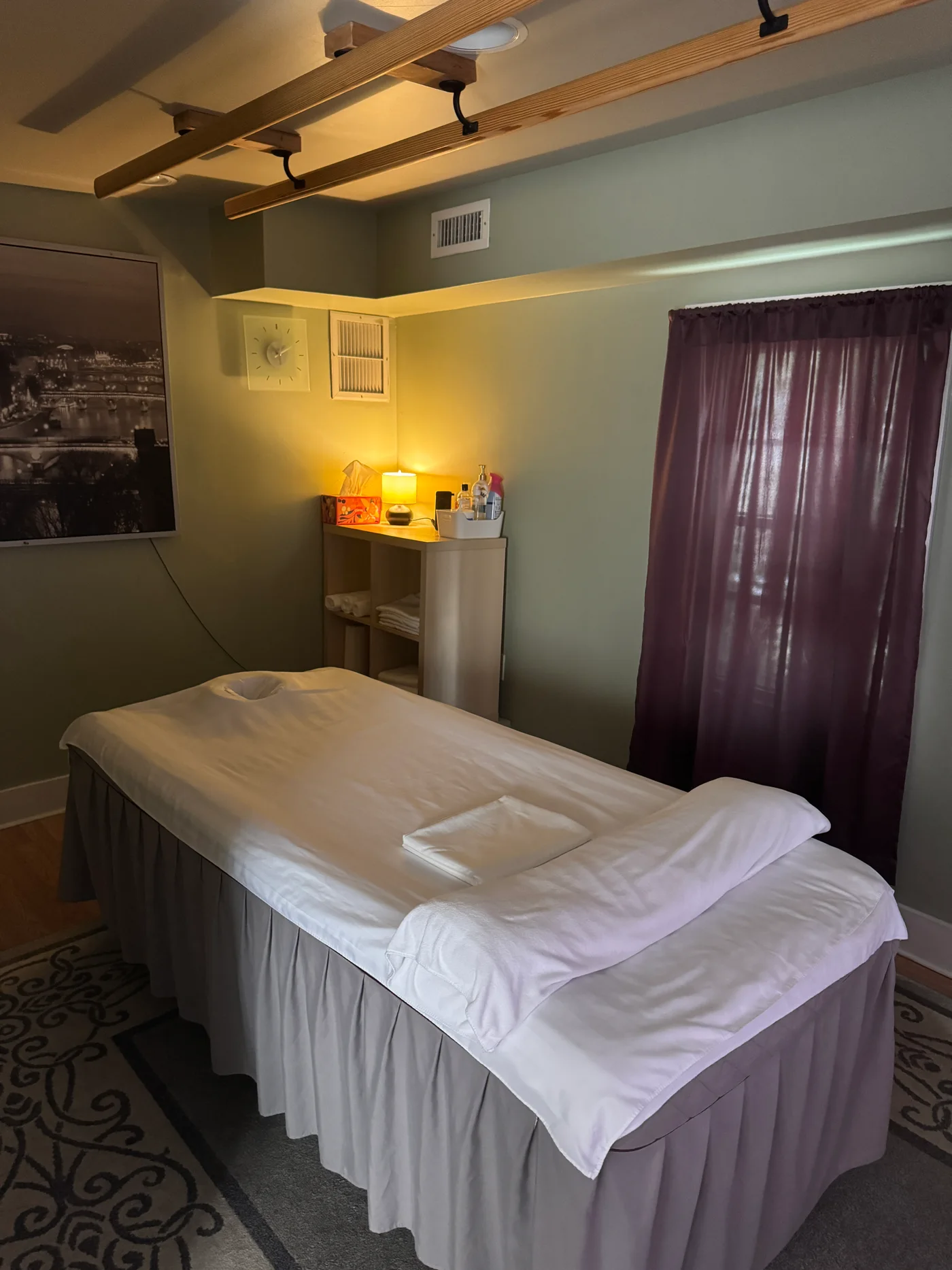 Prepared massage table with white linens and a purple curtain at Wellness Foot Spa in Glenside, PA